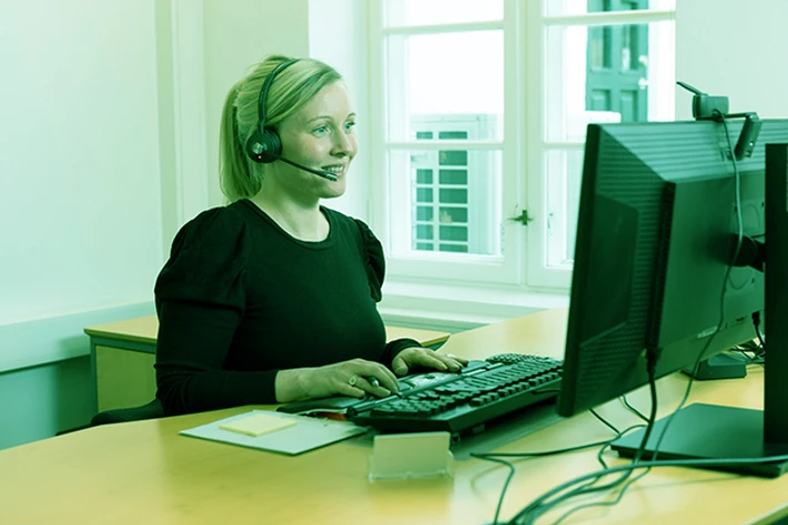Foto af medarbejder med headset på foran computeren