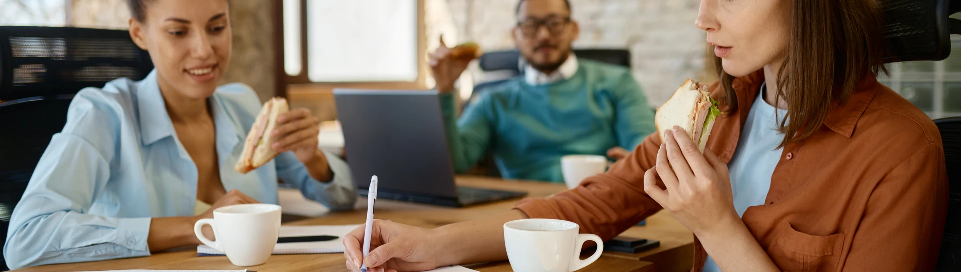 Personer sidder og spiser medens de arbejder